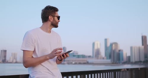 Man Using Smartphone with City Skyline Background