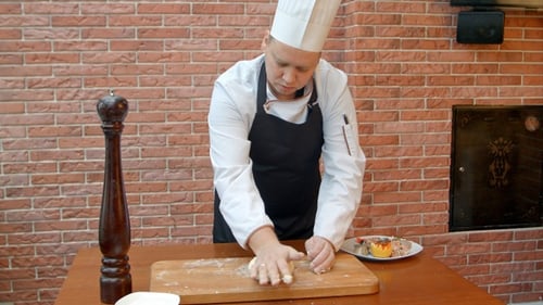 Chef Kneading Dough at a Table Indoors