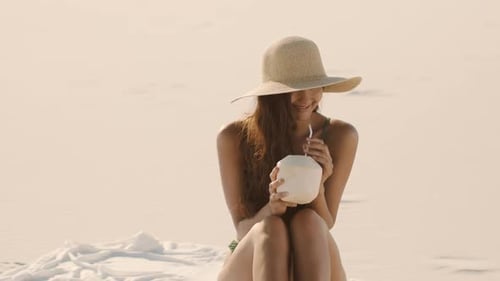 Woman with Coconut Relaxing on the Beach