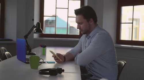 Young Adult Using Smartphone at Table