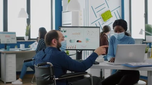 Divers collègues portant des masques faciaux travaillent ensemble dans un nouveau lieu de travail normal