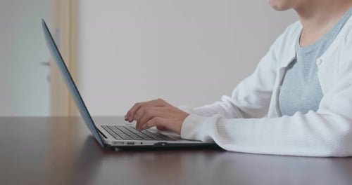 Woman Typing on Laptop at Wooden Desk