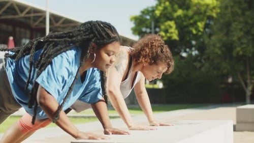 Women Performing Push-Ups on Concrete Block Outdoors