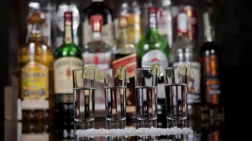 Closeup of a Man and a Woman Taking Shots of Tequila with Lime in a Bar