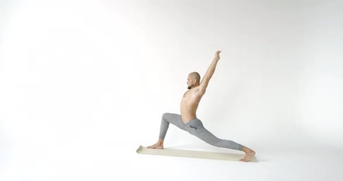Muscular Male Yogi Doing the Pose of a Warrior and Goes Into a Pose the Downward Facing Dog. White