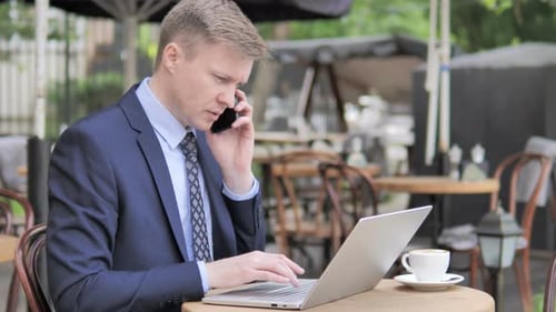 Businessman Talking on Phone while Sitting in Outdoor Cafe