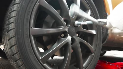 Tightening Lug Nuts On Car Tire with Iron