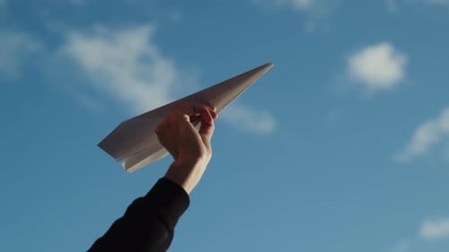 Hand Holding a Paper Airplane in Sky