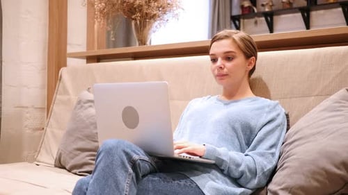Woman Excited While Using a Laptop on the Couch
