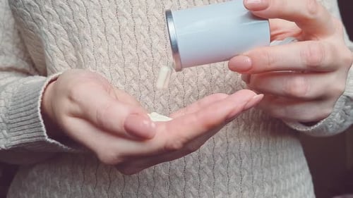 Woman Pours White Pills into Her Hand