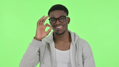African Man Showing Okay Sign on Green Background