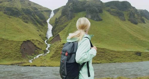 Woman Tourist with Backpack Enjoying an Icelandic Waterfall Near Fjadrargljufur at South Coast of