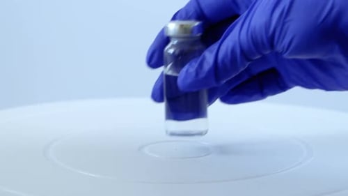 Vaccine Vial and Syringe being Placed on Surface