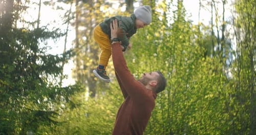 Slow Motion: Father Tossing His Son Into Air Outside