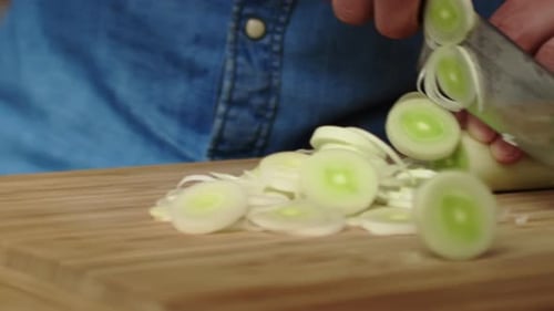 Tracking right video of slicing leek in the kitchen.