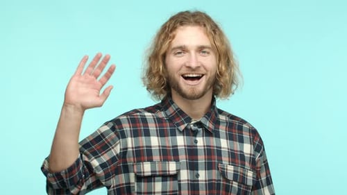Man Waving and Smiling in Front of Blue Backdrop