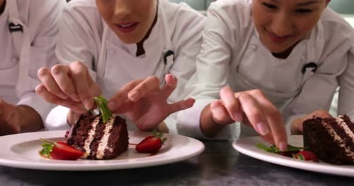 Chefs Plating Slices of Chocolate Cake with Strawberries