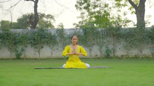 Namaste Yoga pose or Namaskarasana is being done by an Indian woman in a park
