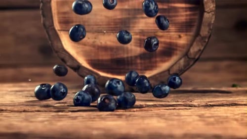 Blueberries Falling onto a Rustic Wooden Table