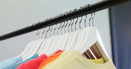 Various t-shirts arranged in a row on cloth rack 4k