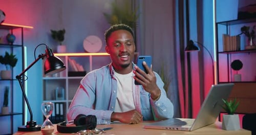 Chico de piel negra disfrutando de una agradable conversación en Vídeo en el móvil en casa