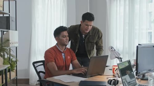 Männliche Kollegen arbeiten im Büro am Laptop