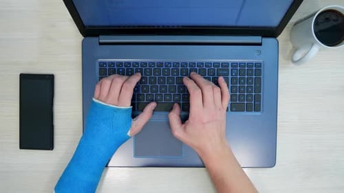 Person With Arm Cast Typing On Laptop