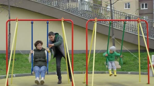Fröhliches kaukasisches Paar und Sohn, die Spaß auf der Spielplatzschaukel haben