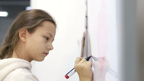Little Schoolgirl Girl Writes a Marker on the Blackboard at School