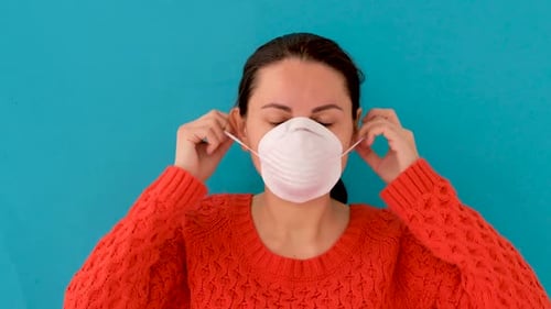 Woman Puts on a Protective White Face Mask