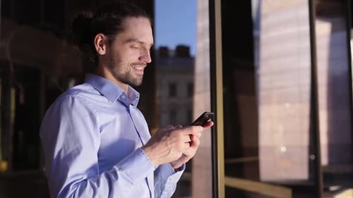 Business Man Using Mobile Phone Near Office Building