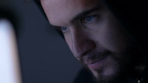 jeune hacker avec des types de capot noir sur l'ordinateur la nuit