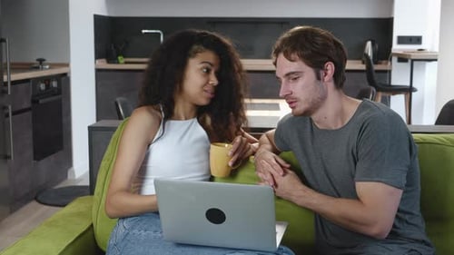 Couple using a laptop on a green sofa