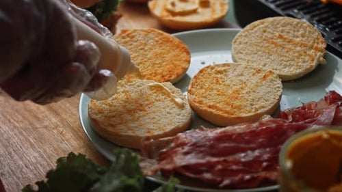 Preparing a Hamburger With Mayonnaise and Bacon