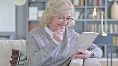 Cheerful Old Woman Celebrating Success on Tablet