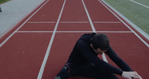 Athlete with Prosthetic Leg Stretches on Track