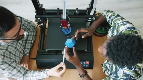 High Angle View of Engineers Discussing 3D Printed Shape Near Working Printer