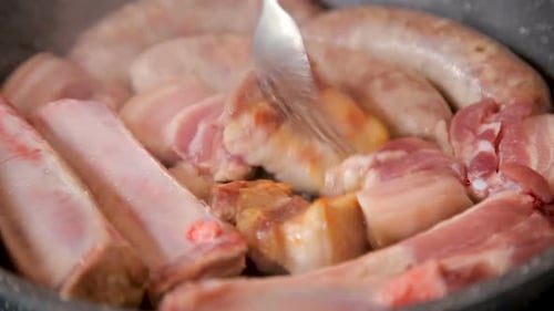 Pork Ribs and Sausages Cooking in Pan