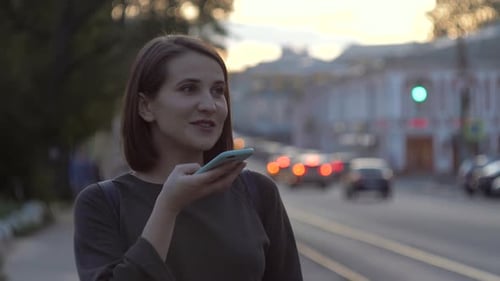 Happy Girl Using a Smart Phone Voice Recognition Audio Message Function on Line Walking on a Street