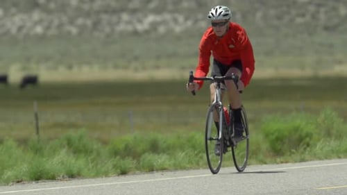 A man road biking on a scenic road.