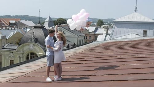 Couple Holding Balloons Embrace on Rooftop Overlooking City