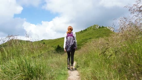 Woman Hikes Mountain Trail on Sunny Day