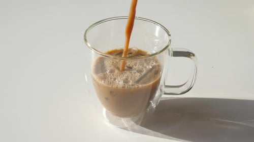 Coffee Pouring into Mug Filled with Ice