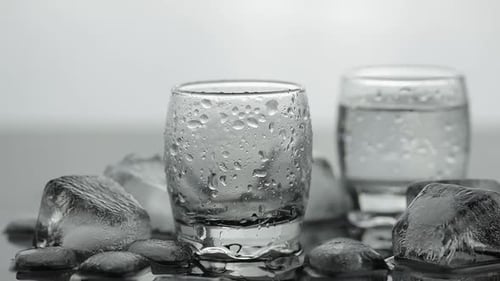 Pouring Up Shot of Vodka From a Bottle Into Glass. White Background