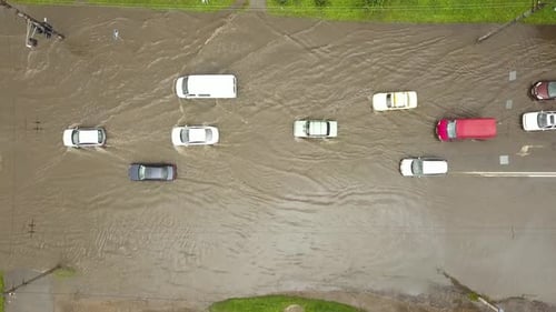 Aerial view of traffic cars driving on flooded road with rain water.