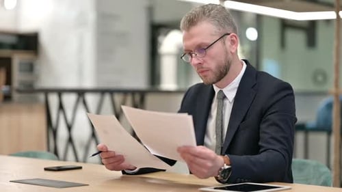 Hardworking Young Businessman Reading Documents in Office