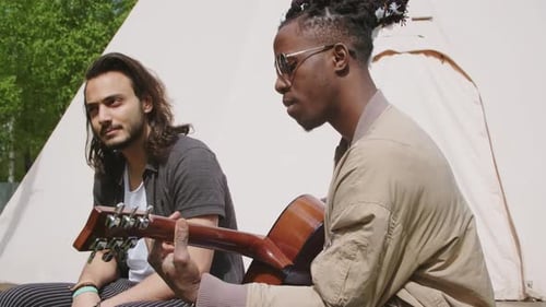 Young Adults Relaxing and Playing Guitar Outdoors