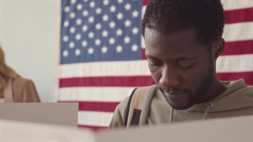 Young Adult Voting with American Flag Backdrop