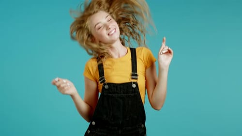Beautiful Woman Dancing Energetically and Actively on Blue Studio Background. Cute Girl's Portrait