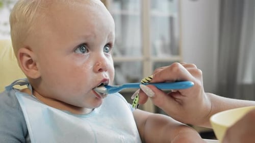 Adorable Blond Infant Being Fed with a Spoon